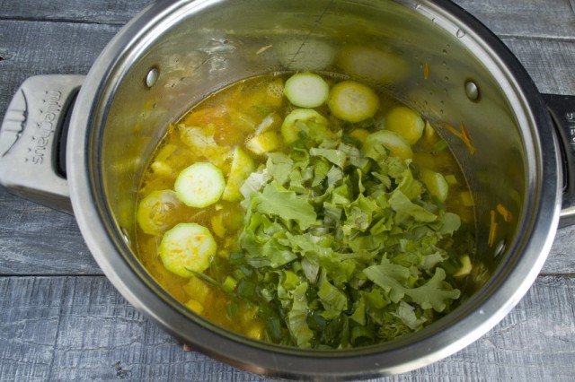 Наливаем в кастрюлю бульон, доводим до кипения и добавляем зелень и салат