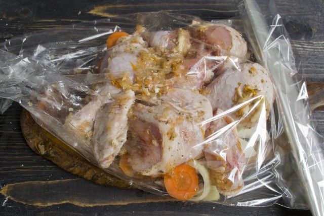 Смазываем маринованную курицу маслом и выкладываем на овощную подушку в рукав для запекания