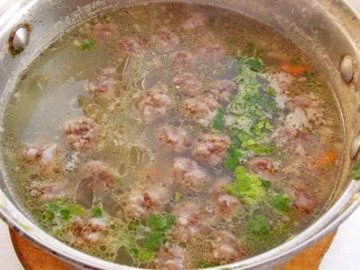 Добавляем в суп лук и фрикадельки. Варим 5-6 минут, добавляем зелень и специи